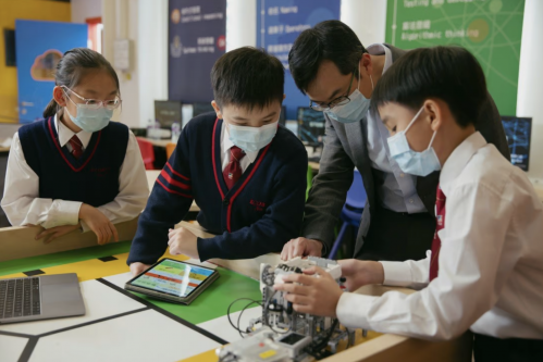 Three students at a small table working with a teacher on a project