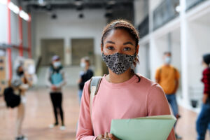 Portrait of african-american student with face mask back at college or university, coronavirus concept.