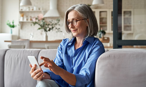 Gray haired woman at home scrolling on phone