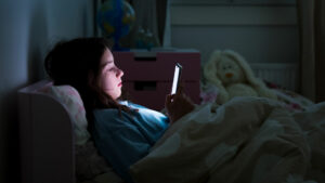 Child reading phone screen in the dark in bed