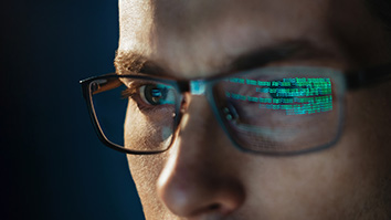 Code reflected in a man's eyeglasses