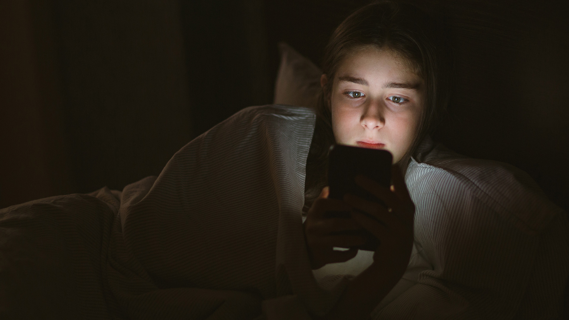teen looking at a phone screen in the dark