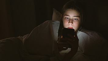 teen looking at a phone screen in the dark