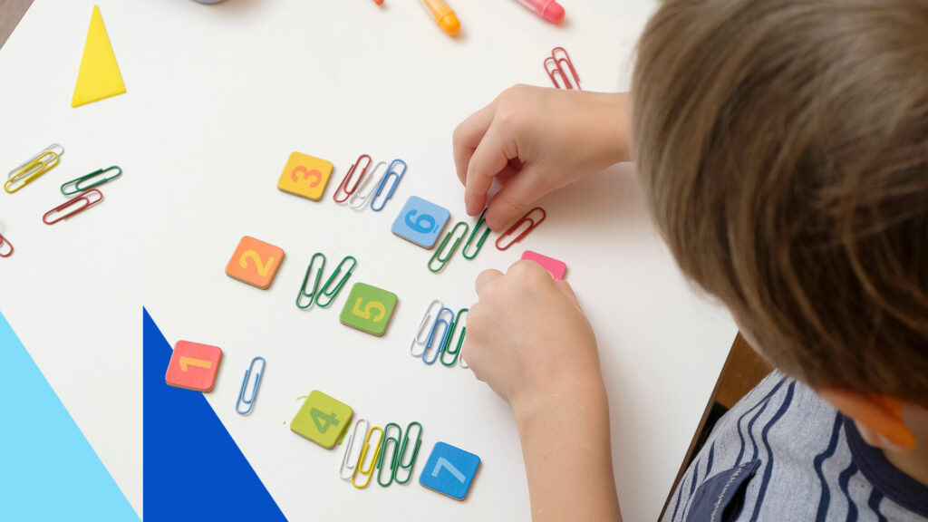 A child playing with numbers and paperclips on a table